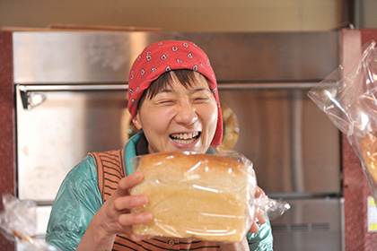 焼き上がったパンを手に笑顔の伊富貴さん